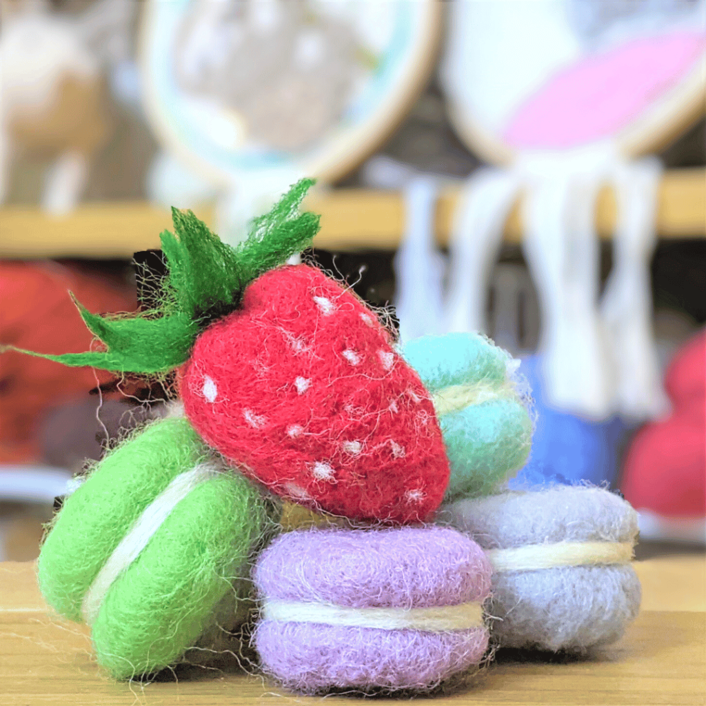 image shows realistic needle felted strawberry and macarons