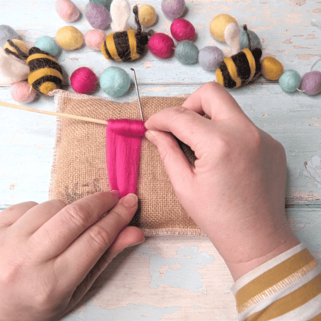 Image shows a person making needle felted balls