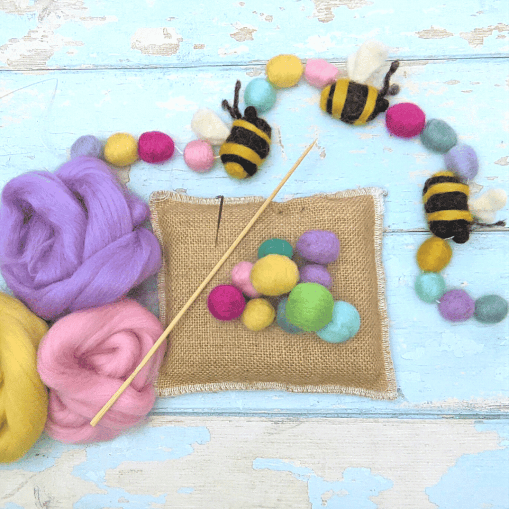 image shows a needle felting mat and tools thatare needed to create spring needle felted garlands
